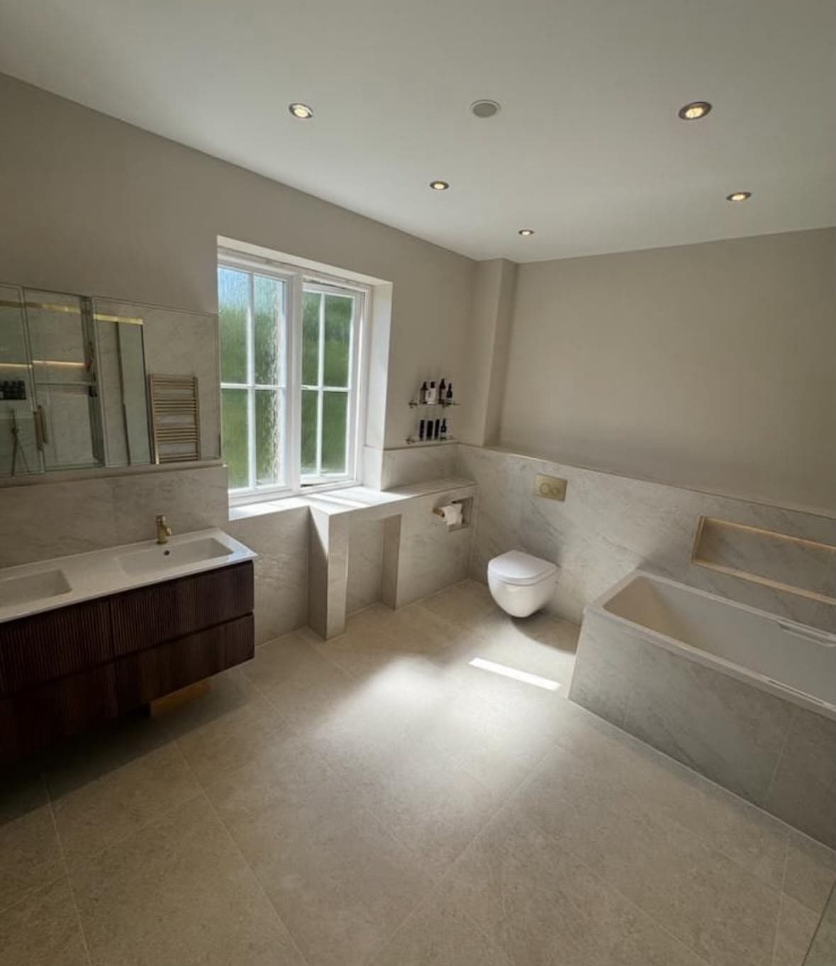 Spacious luxury bathroom with large stone tiles and designer bath surround