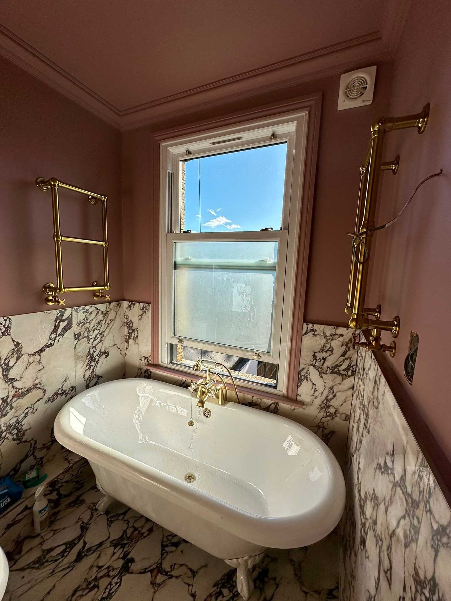 Roll-top clawfoot bath with Arabescato marble and polished brass fittings